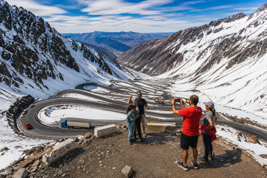 Vista panorámica de Los Caracoles en la Curva 17 del Camino Internacional Los Libertadores, con los turistas disfrutando de las impresionantes vistas de la Cordillera de los Andes.